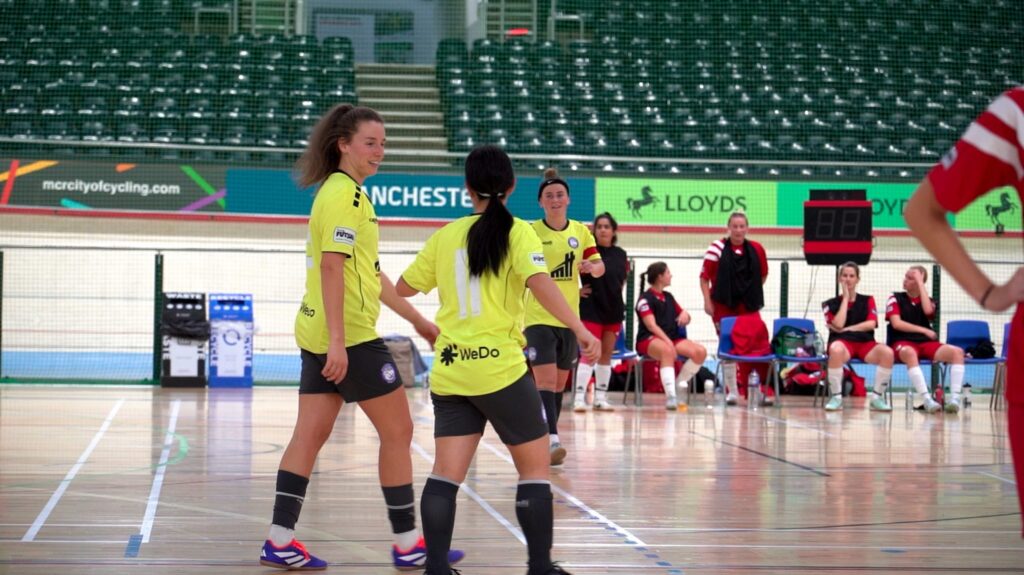Women futsal players during a competitive indoor match at a UK futsal venue.